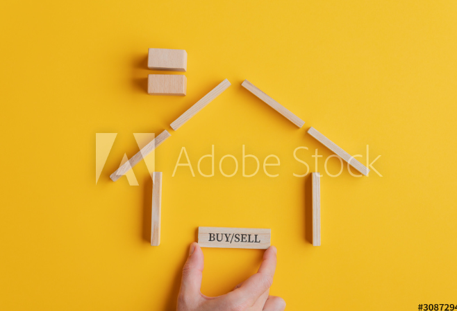 A house represented with wood sticks on a yellow table.