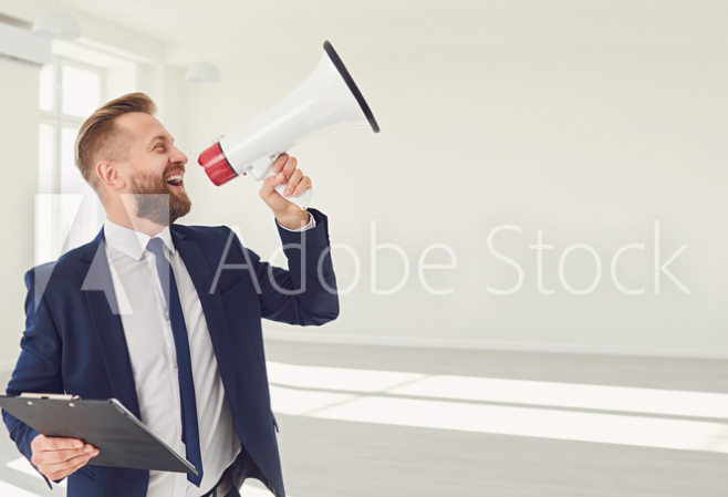 A man in a empty room using a megaphone.